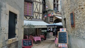 A narrow cobblestone street with a restaurant named "RESTAURANT" and outdoor seating with red and white checkered tablecloths. - Dordogne gite, amazing views, private heated pool, large gardens, NO ADDED COSTS (Marnac)