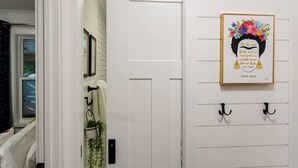 A hallway with a white door, a framed quote on the wall, and a plant. - Rise & Grind SLC HIGH-END Style/Gated n Garage-2Br (South Salt Lake)