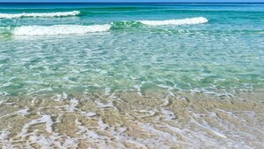 A beach with clear turquoise water and gentle waves.