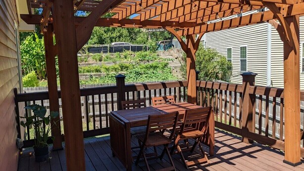 A wooden deck with a pergola, a table with chairs, and a potted plant. - Casa Rosa - 2BR West End Bungalow (Durham)