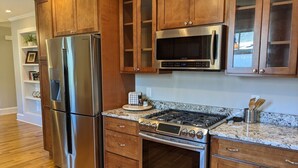 A kitchen with stainless steel appliances, wooden cabinets, granite countertops, and a built-in oven. - Casa Rosa - 2BR West End Bungalow (Durham)