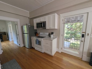 A kitchen with white cabinets, a stainless steel refrigerator, a microwave, and an oven.