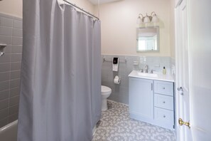 Un baño con cortina de ducha, inodoro, lavabo y armario.