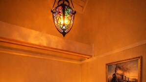 Une chambre à coucher avec un lit en bois, deux lampes de chevet, un lustre en vitrail et un tableau au mur.