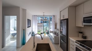Una cocina moderna con una isla central, electrodomésticos de acero inoxidable y vistas al exterior.