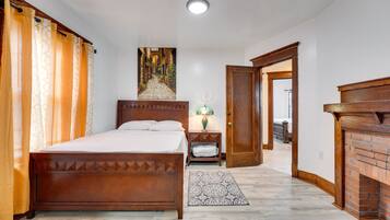 A bedroom with a wooden bed, a nightstand, a lamp, a patterned rug, and a fireplace.