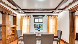 A dining area with a wooden table, two chairs, a vase with flowers, and a painting on the wall. - Buffalo Vacation Rental ~ 20 Mi to Niagara Falls! (Buffalo)