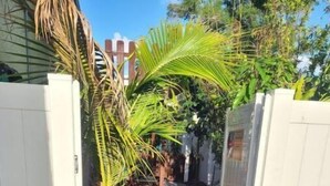 A narrow paved pathway flanked by white fences, leading to a building with a white exterior. - Tropical Paradise studio #3 (Tampa)