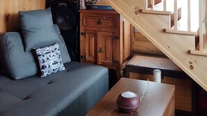 Una escalera de madera conduce a una zona superior con un sofá y una mesa. Se ve una obra de arte con la figura de un toro en la pared.