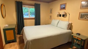 Una camera da letto con un letto, un comodino, una finestra con tende e lampade a parete.