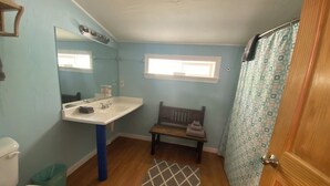 A bathroom with a white sink, a mirror, a toilet, a bench, and a shower curtain. - The Rock Climbing Suite (Nevada city)