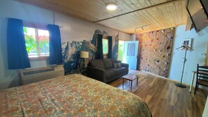 A room with a bed, a sofa, a climbing wall, and a door leading outside. - The Rock Climbing Suite (Nevada city)
