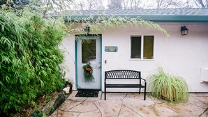 A house with a stone patio, a bench, a door with a wreath, and a small window with shutters. - The Rock Climbing Suite (Nevada city)