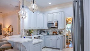 A kitchen with white cabinetry, a built-in oven, and a large island with stools.