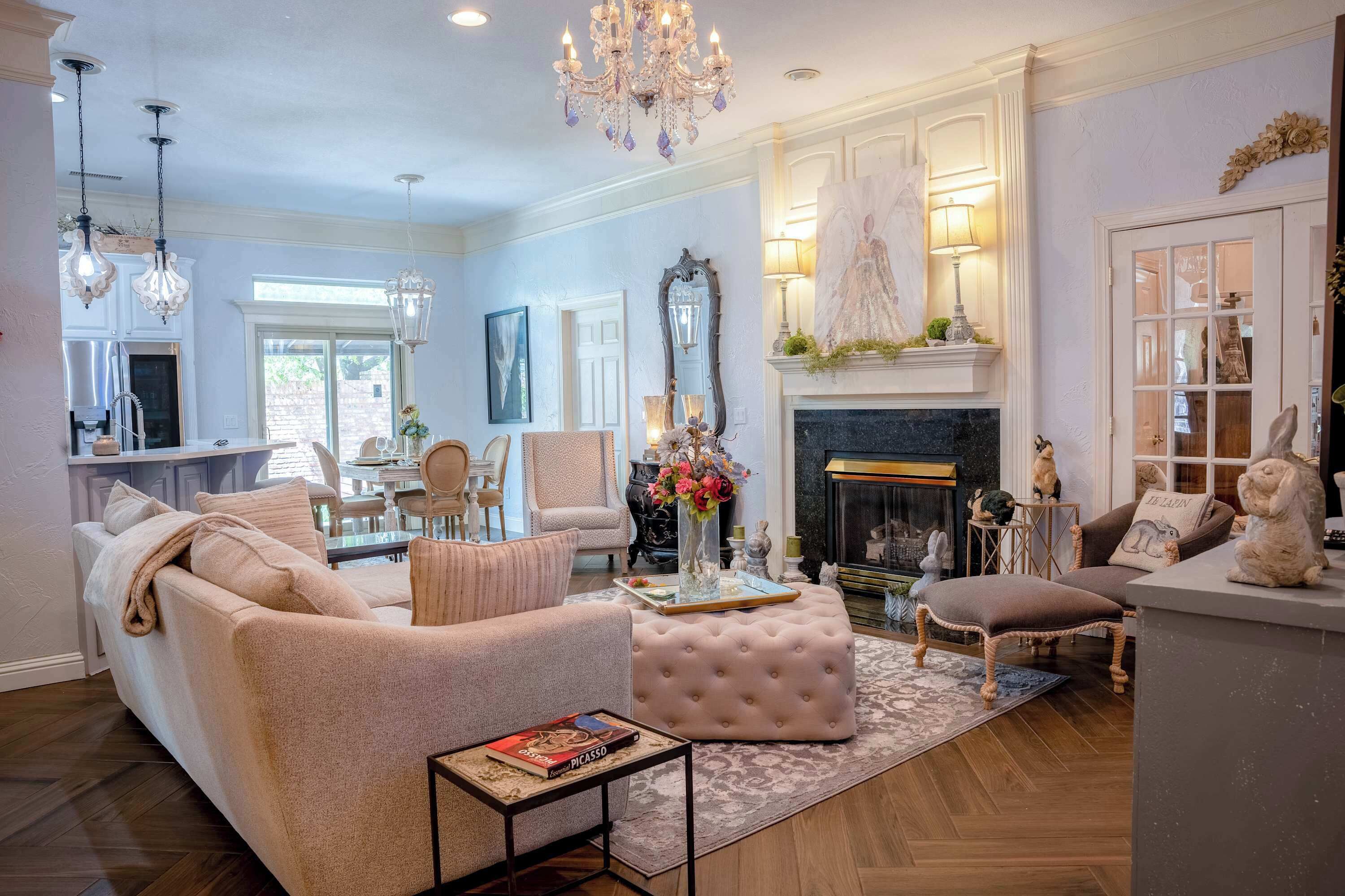 A living room with a sofa, ottoman, and coffee table, a fireplace, and a dining area with chairs and a table.