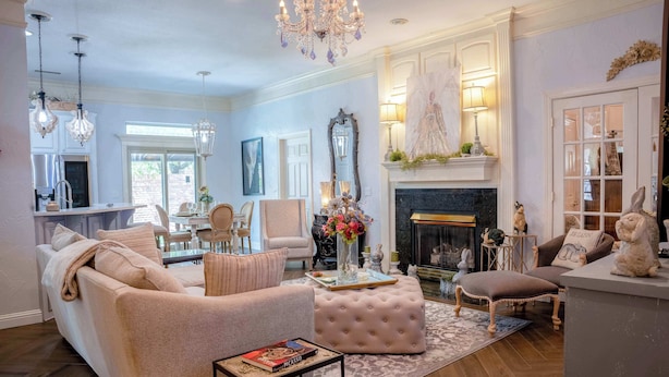 A living room with a sofa, ottoman, and coffee table, a fireplace, and a dining area with chairs and a table.