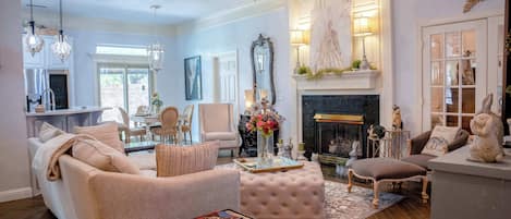 A living room with a sofa, ottoman, and coffee table, a fireplace, and a dining area with chairs and a table.