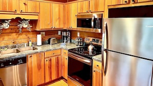 A kitchen with wooden cabinets, stainless steel appliances, and granite countertops. - 6BR Log Cabin | Walk to Downtown | Mountain Views (West Jefferson)