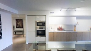 Modern kitchen with stainless steel appliances, wooden countertop, and glass coffee table.