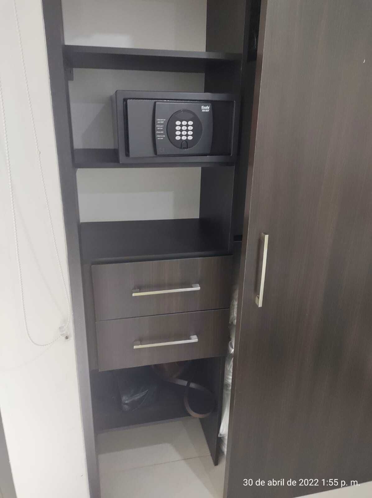 A dark wooden wardrobe with a microwave on top and two drawers.