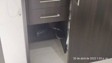 A dark wooden wardrobe with a microwave on top and two drawers.