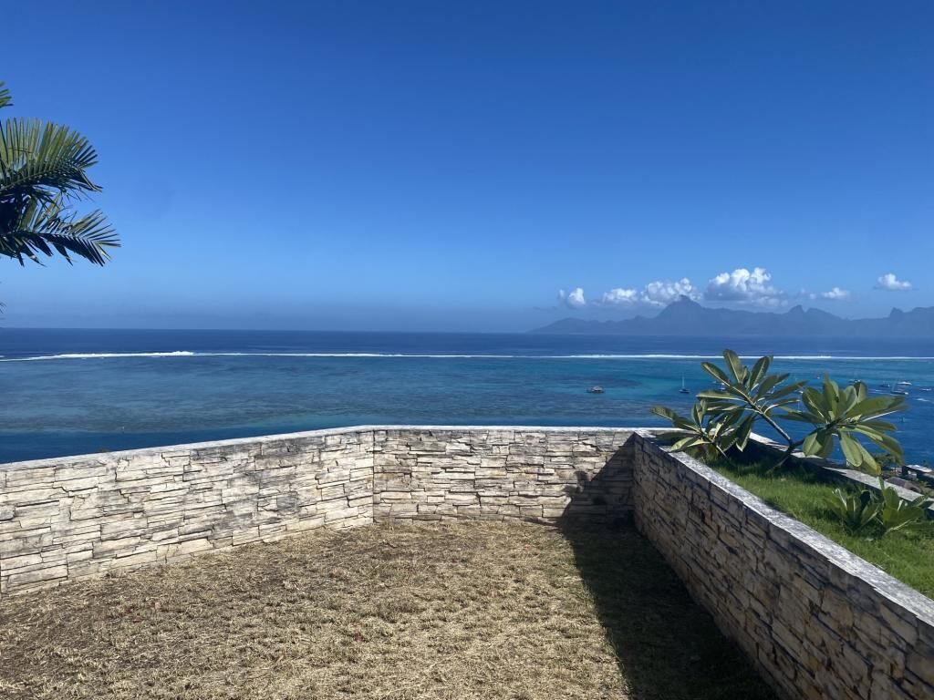Une terrasse en pierre offrant une vue sur l’océan et les montagnes.