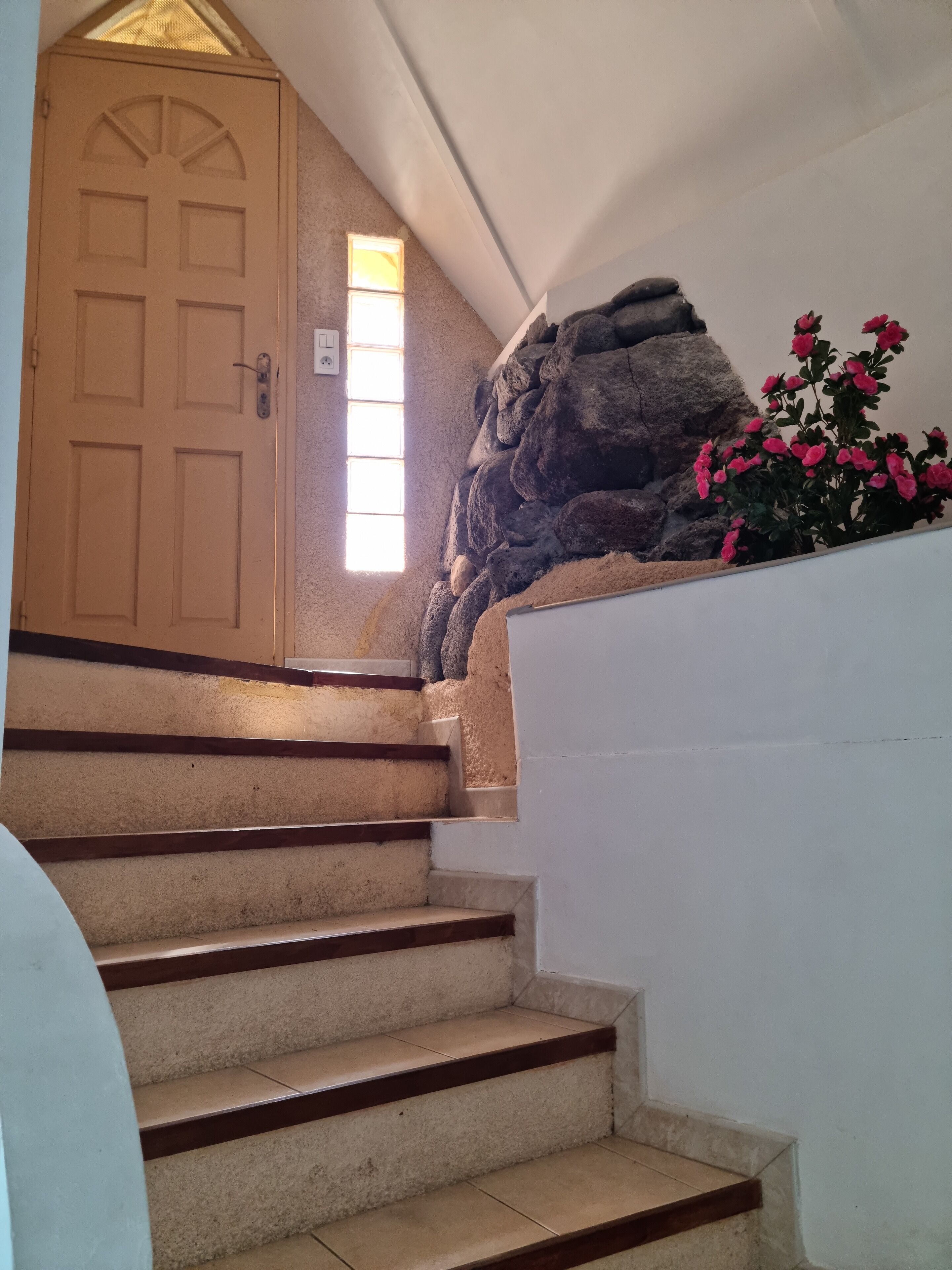 A staircase with beige steps and wooden handrails, leading to a beige door with a window above it.