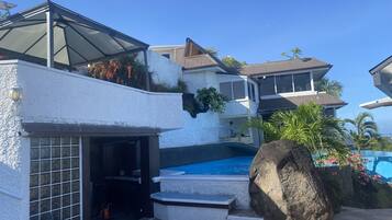 Una propiedad residencial con piscina, patio de piedra y zona exterior cubierta.