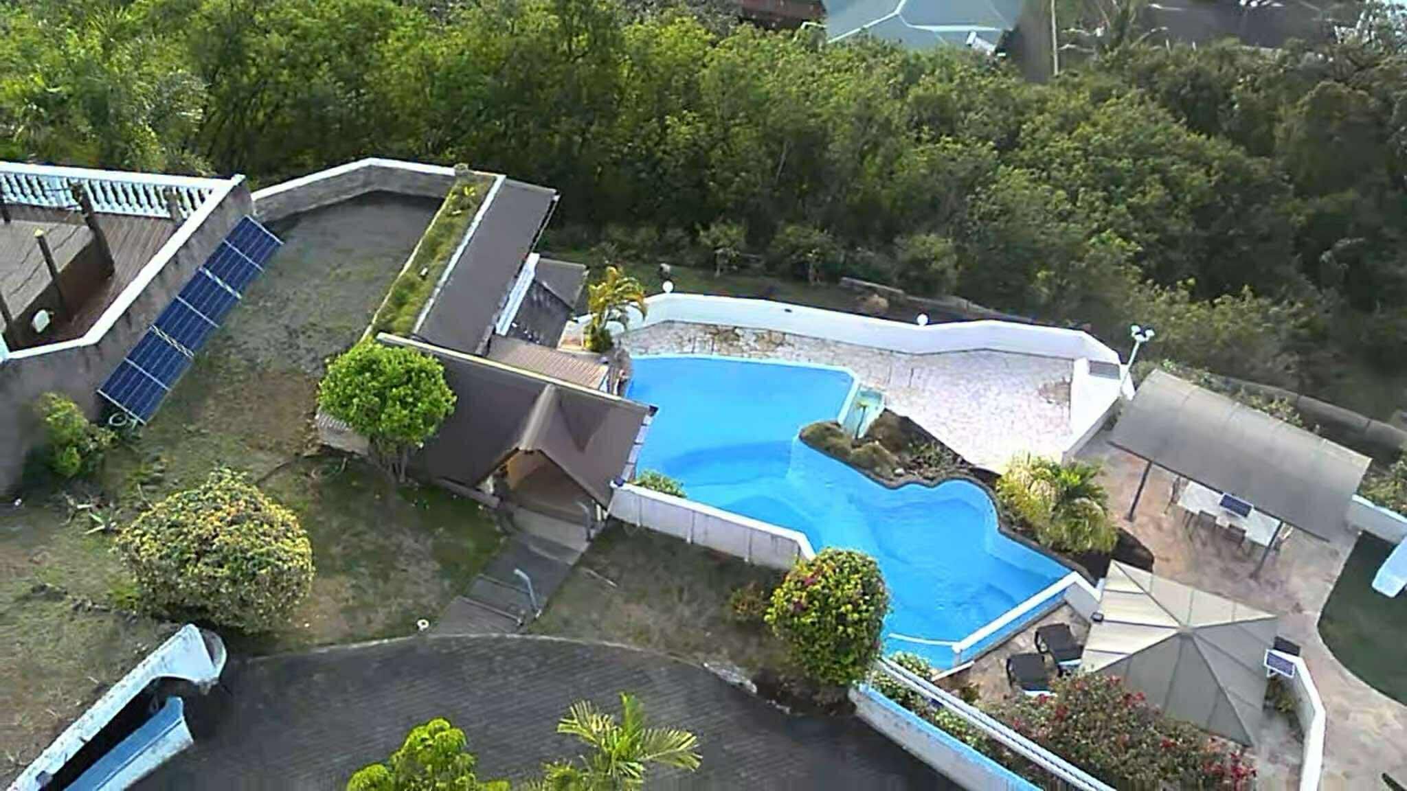 Una propietat residencial amb piscina, panells solars i un jardí tancat per una tanca.