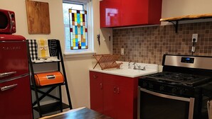 Eine Küche mit einem roten Kühlschrank, einem Holztisch und einem Herd.