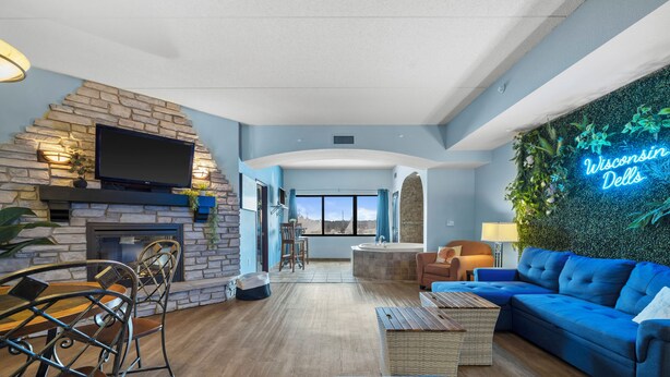Una sala moderna con chimenea de piedra, televisor de pantalla plana, sofá azul y un letrero de neón que dice "Wisconsin Dells".