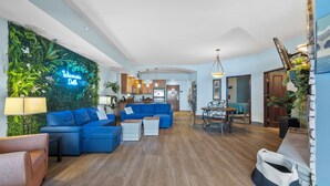 Una sala de estar moderna con un sofá azul, un comedor y una cocina al fondo.