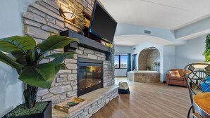 Una sala de estar moderna con una chimenea de piedra, un televisor de pantalla plana montado encima y una planta grande.