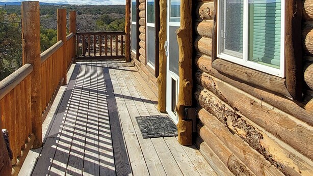 Une cabane en rondins dotée d’une terrasse en bois et de grandes fenêtres.
