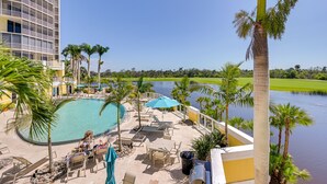 A resort pool area with lounge chairs, umbrellas, and a view of a river. - Estero Resort Condo w/ 2 Pools & Tennis Center! (Estero)