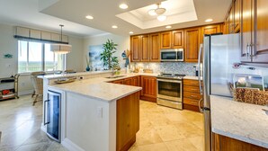 A modern kitchen with wooden cabinets, stainless steel appliances, and a large island. - Estero Resort Condo w/ 2 Pools & Tennis Center! (Estero)