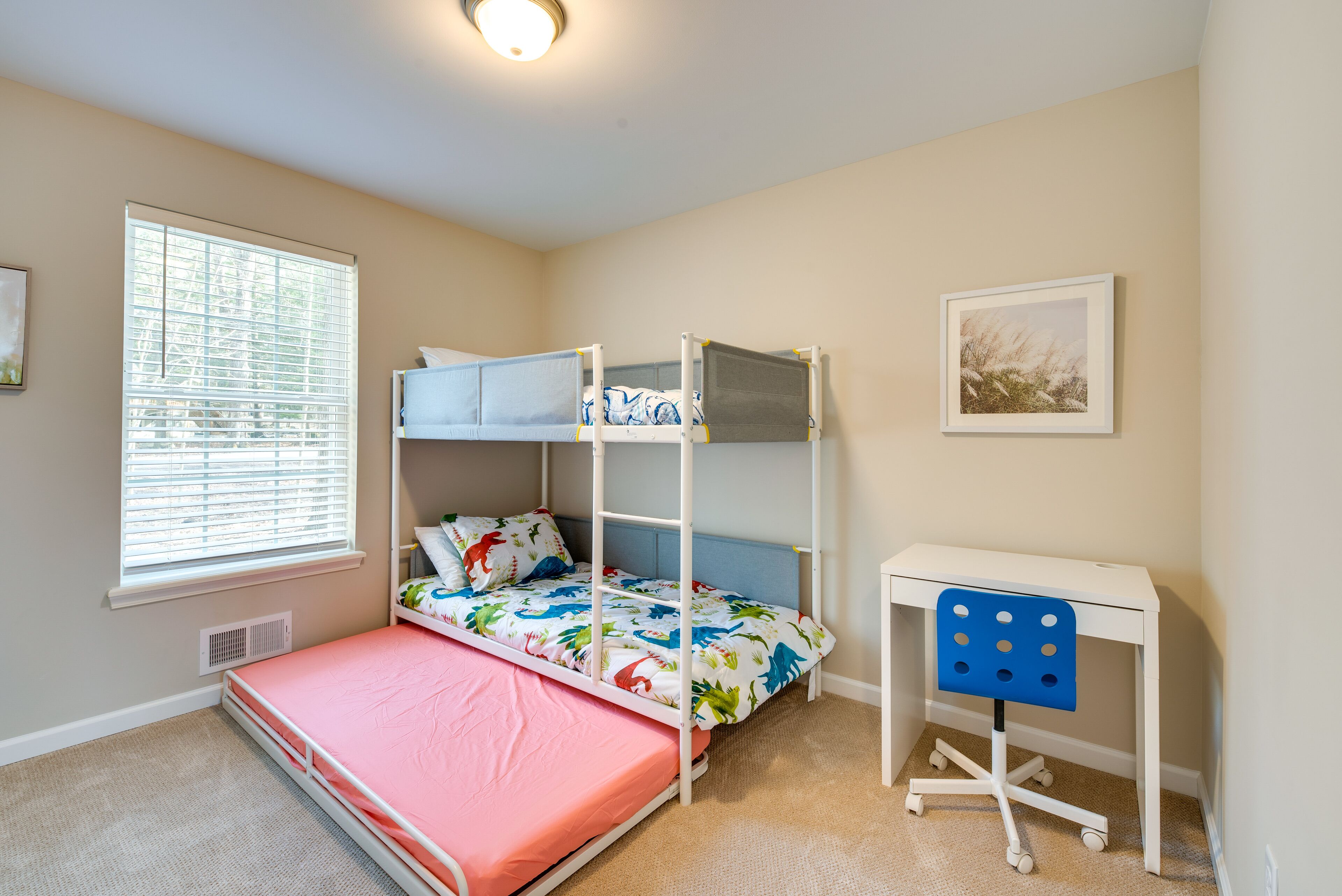 Een kamer met stapelbedden, een bureau en een raam met zonwering.