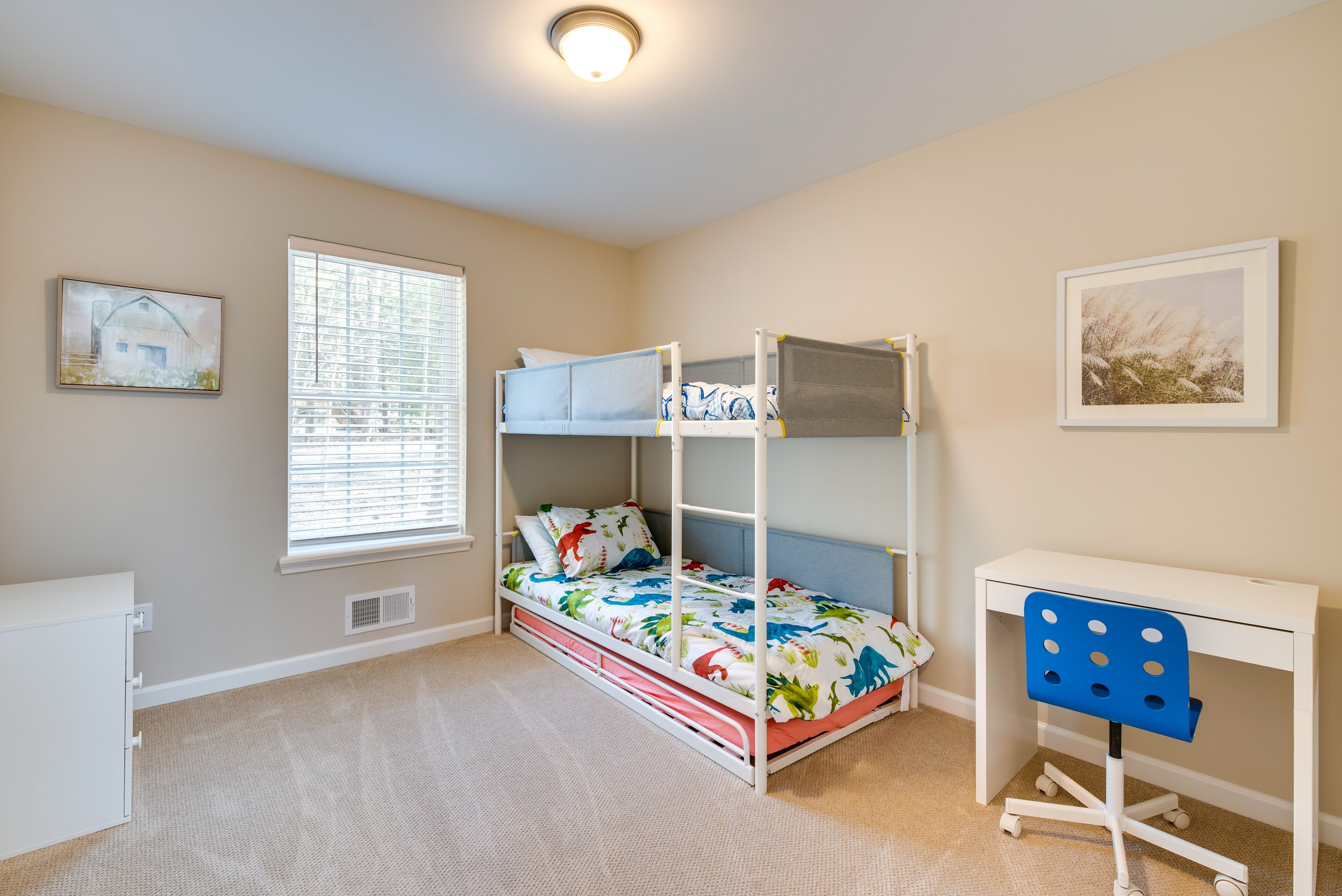 A bedroom with bunk beds, a desk, and a chair.