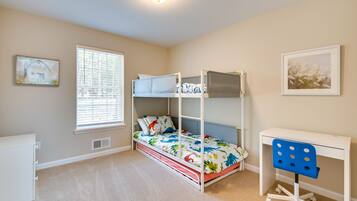 A bedroom with bunk beds, a desk, and a chair.