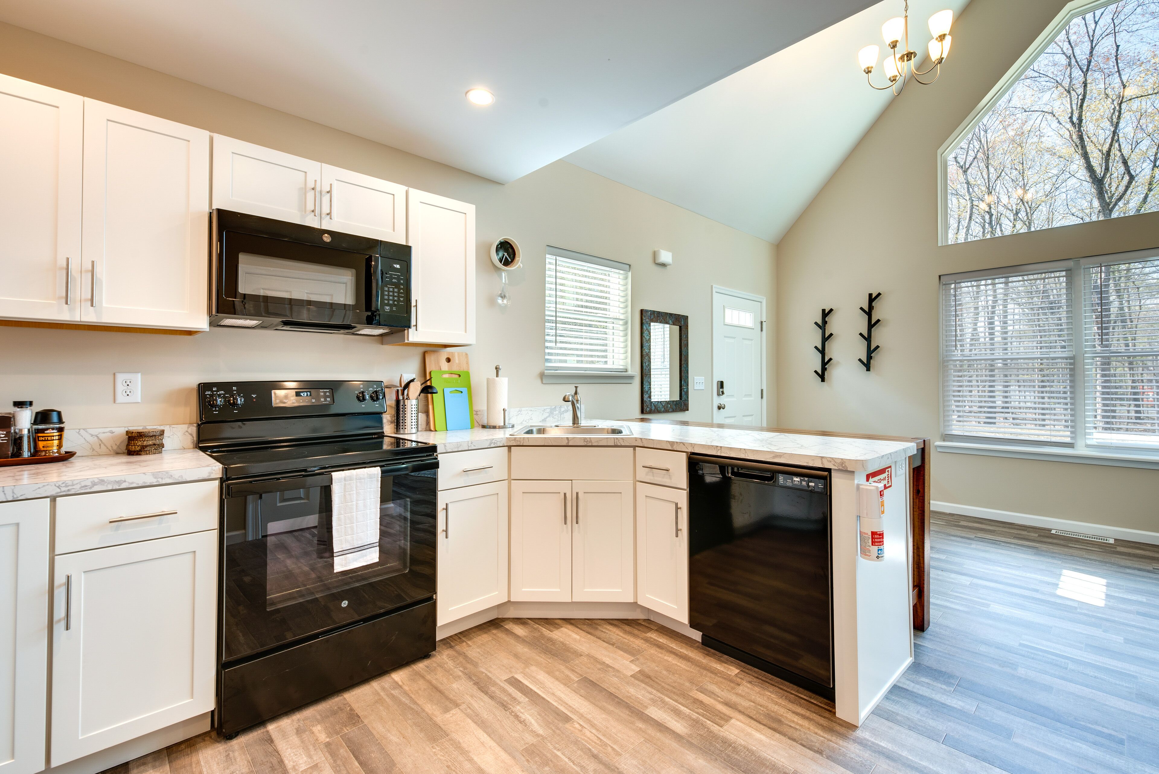 A modern kitchen with white cabinets, a black stove, and a dishwasher.