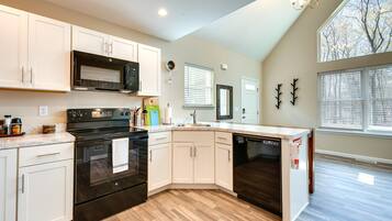 A modern kitchen with white cabinets, a black stove, and a dishwasher.