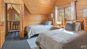 Een knus slaapkamer in een chalet met twee bedden, een houten plafond en een raam met zonwering.
