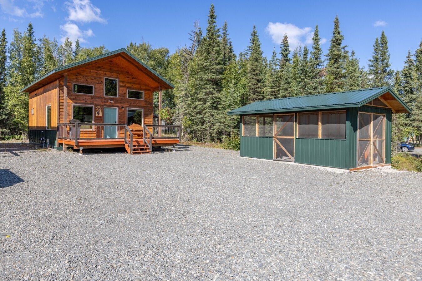 A cabin with a porch and a separate building with a green roof.