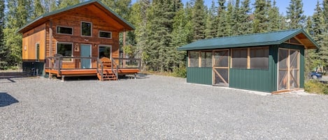 Une cabane dotée d’une véranda et d’un bâtiment séparé surmonté d’un toit végétalisé.
