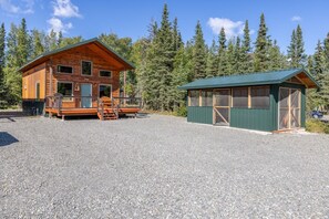 A cabin with a porch and a separate building with a green roof. - Kenai Cozy Cabin - 2 (Kenai)