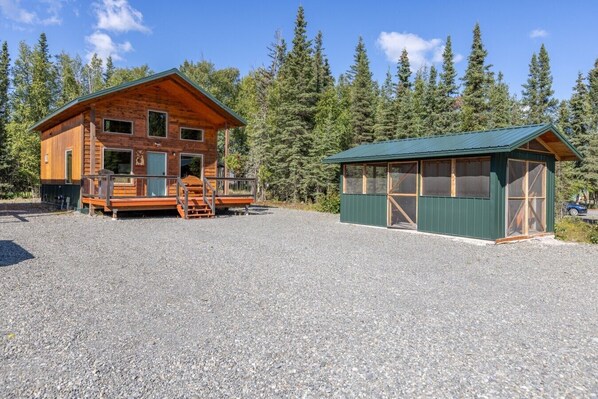A cabin with a porch and a separate building with a green roof.