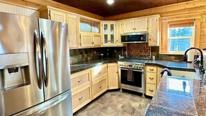 A modern kitchen with wooden cabinets, stainless steel appliances, and a granite countertop.