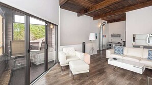 A modern living room with a glass sliding door, a white sofa, a coffee table, and a wooden ceiling. - Canal Front Golf Retreat w/Dock (Ocean Pines)