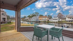 A wooden deck with a table and chairs overlooking a body of water and houses. - Canal Front Golf Retreat w/Dock (Ocean Pines)