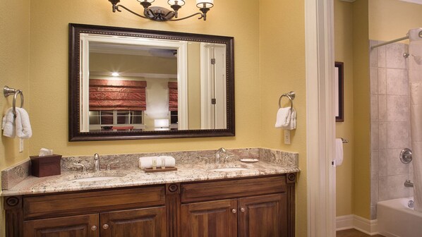 A bathroom with a double vanity, a large mirror, and a shower area.